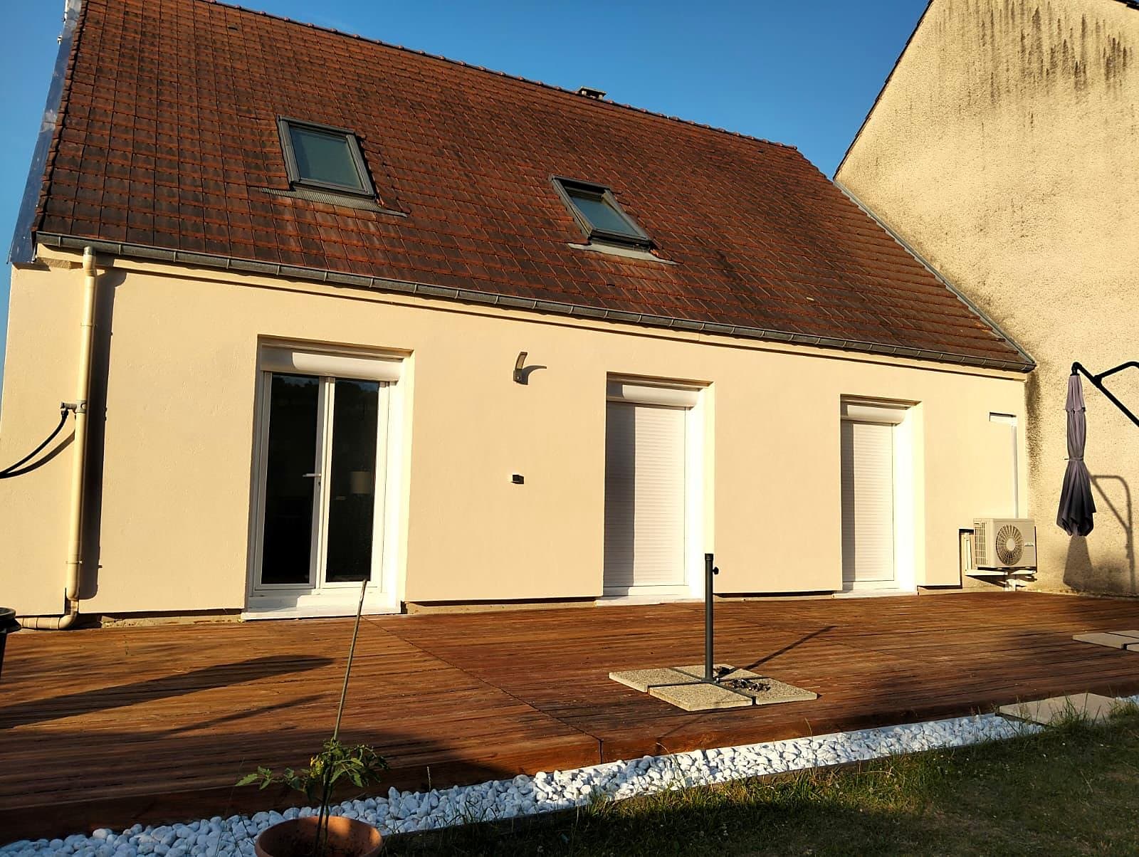Façade isolée par l'extérieur côté jardin, avec l'unité extérieure d'une pompe à chaleur au pied du mur